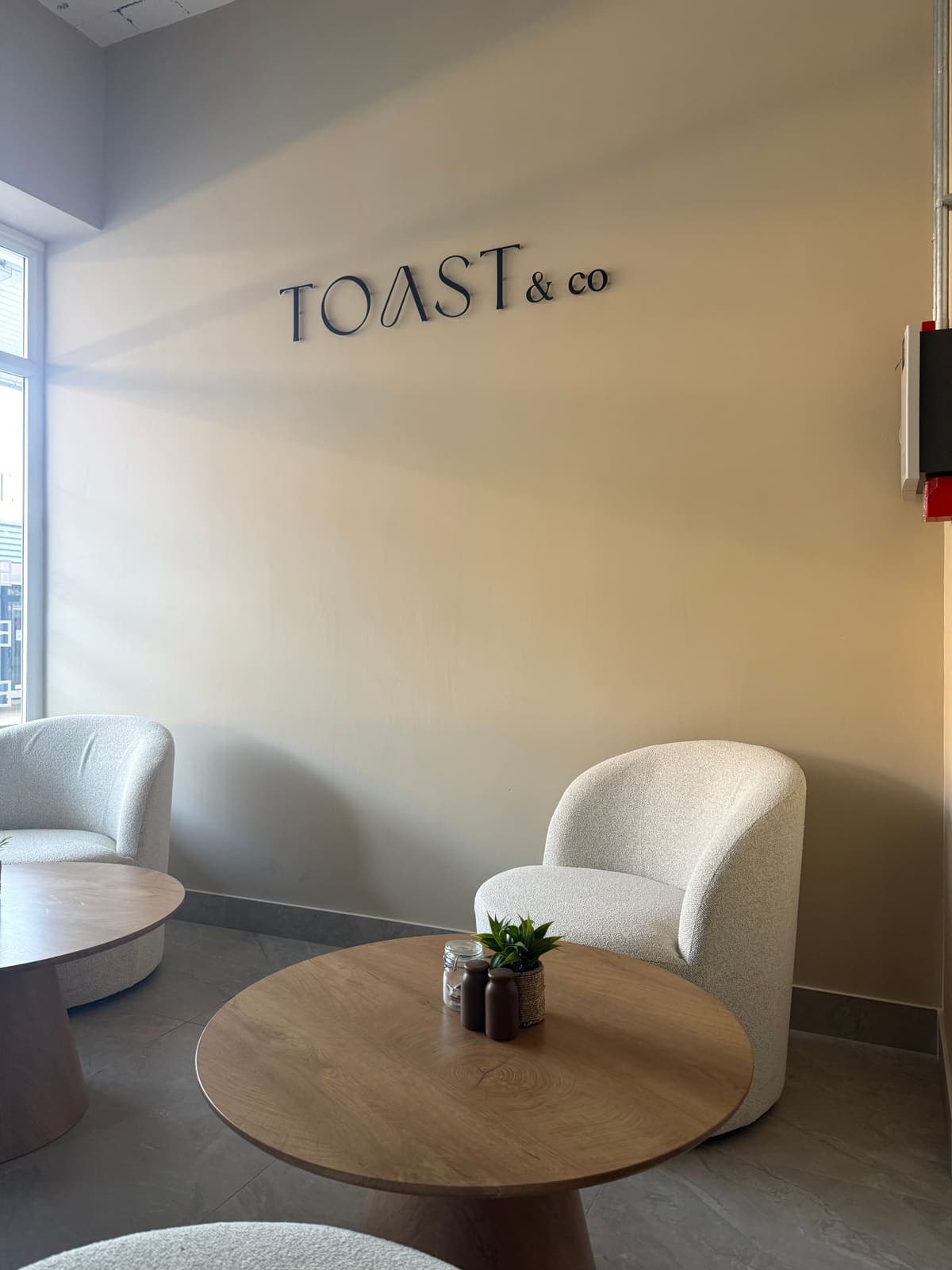 The TOAST & Co sign above soft bouclé armchairs and round oak tables in the Derby café