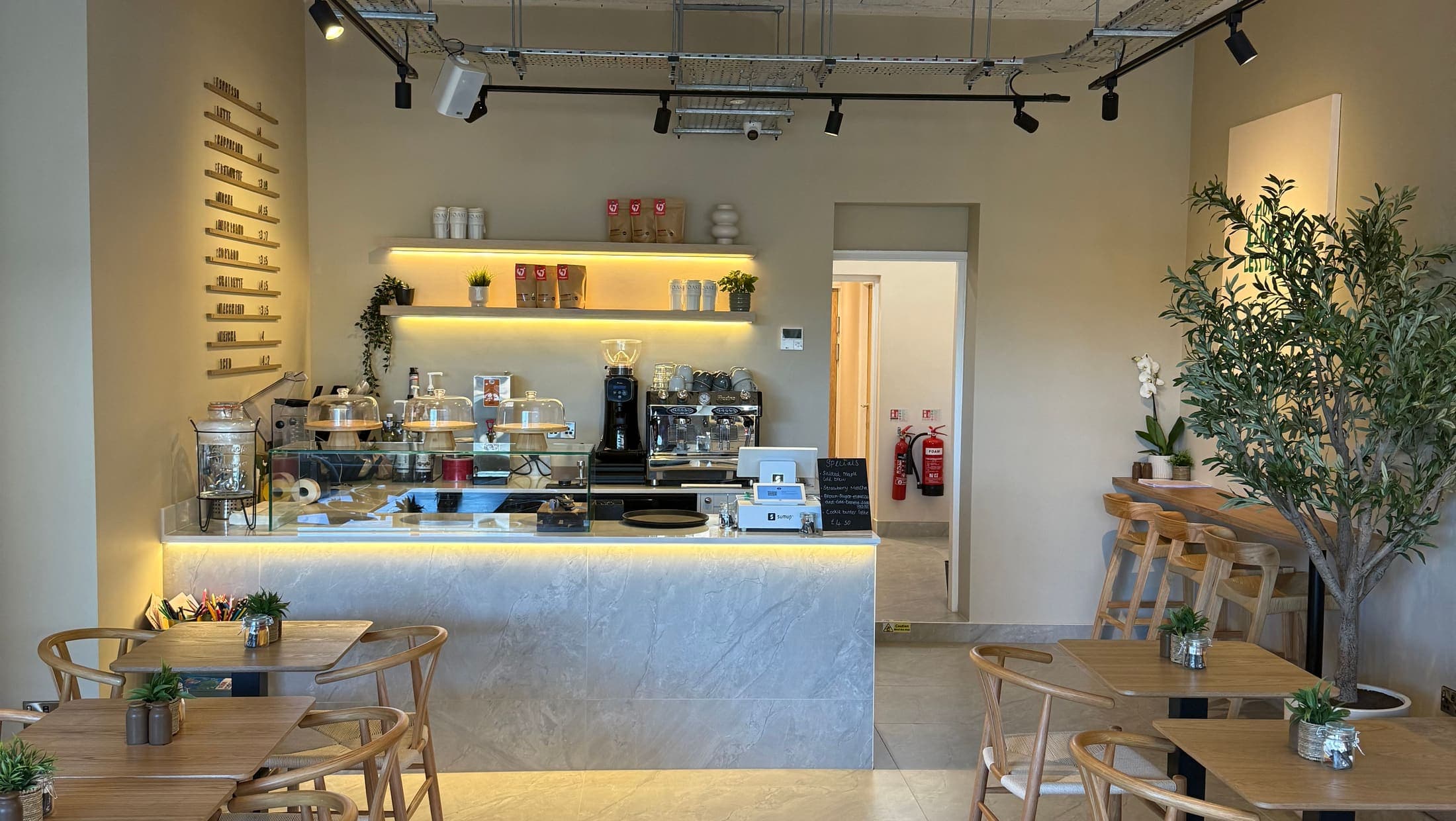 The light, plant-filled interior of TOAST & Co café in Allestree, Derby, with the coffee counter and oak tables
