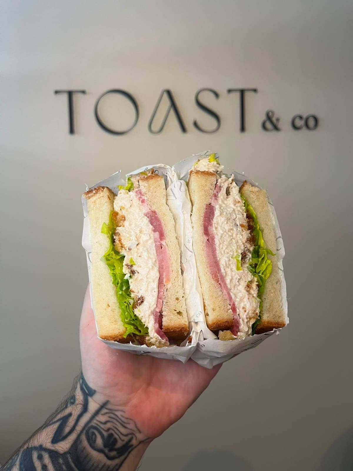 Chicken sandwich with pulled chicken, romaine lettuce, Caesar sauce, crouton crumb and dry cured smoked bacon
